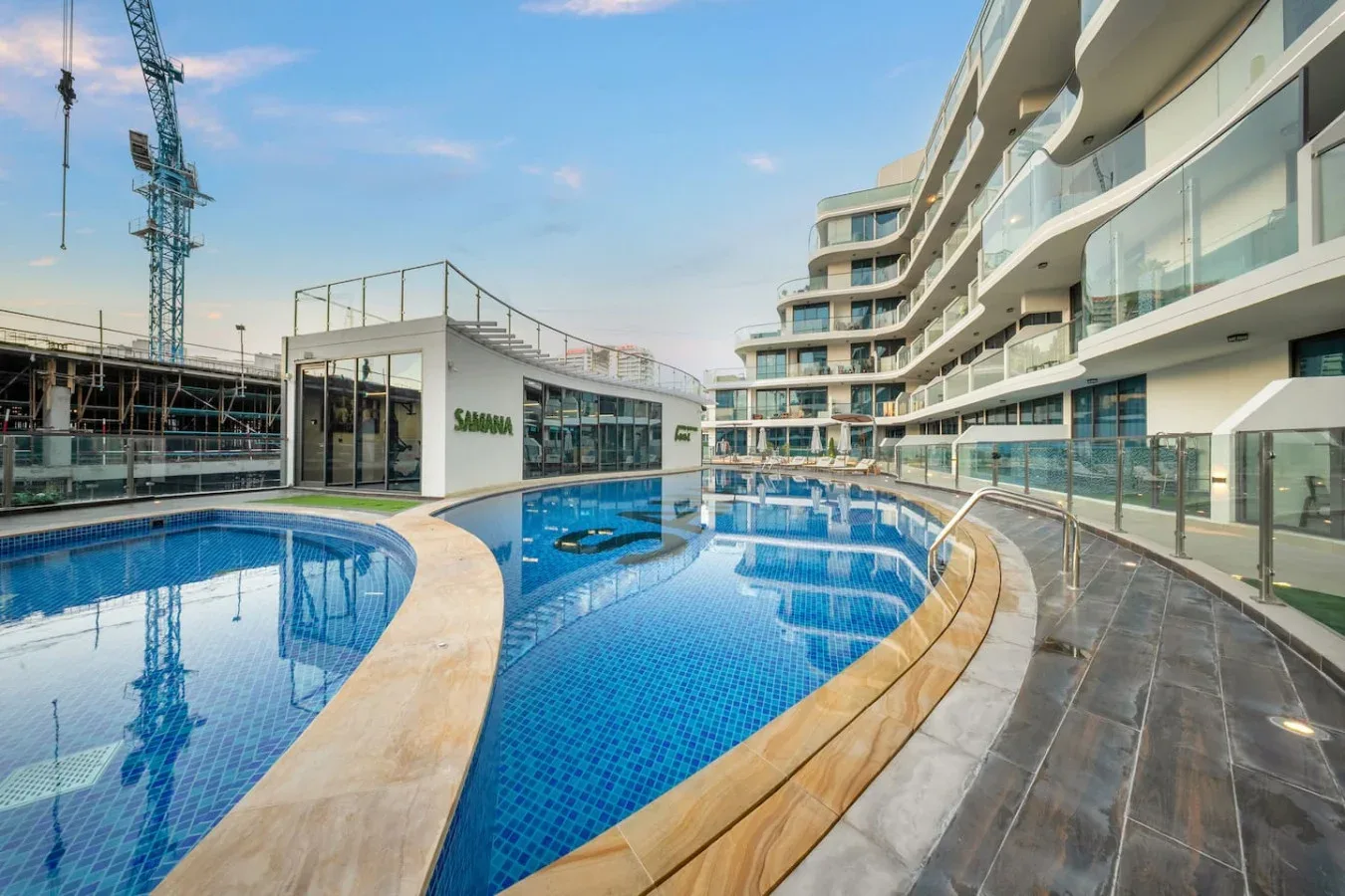 An outdoor swimming pool beside a modern building, with curved walkways along the water.