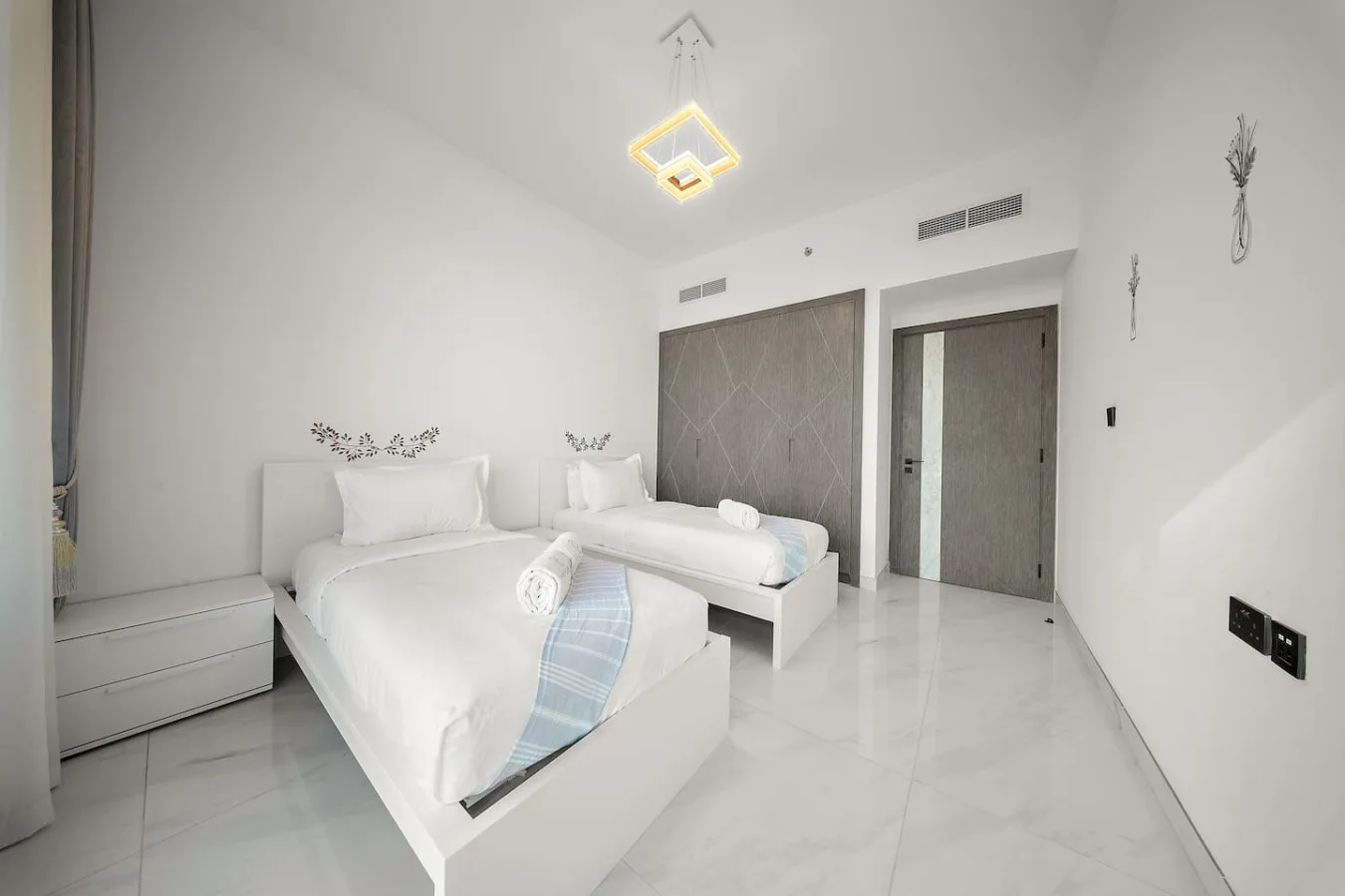 A bright bedroom with two beds and white bedding.