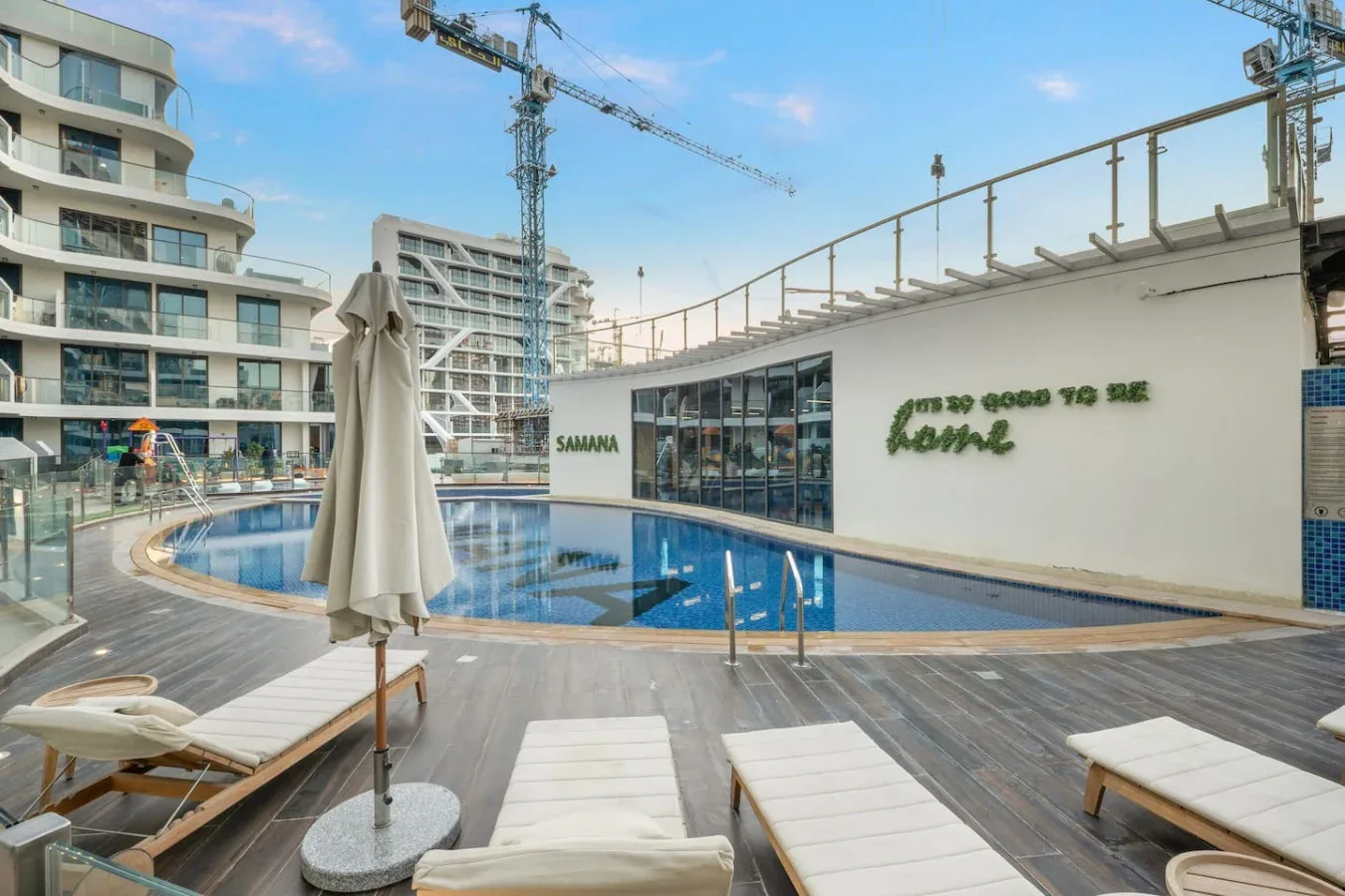 A rooftop pool area with lounge seating and a covered umbrella.