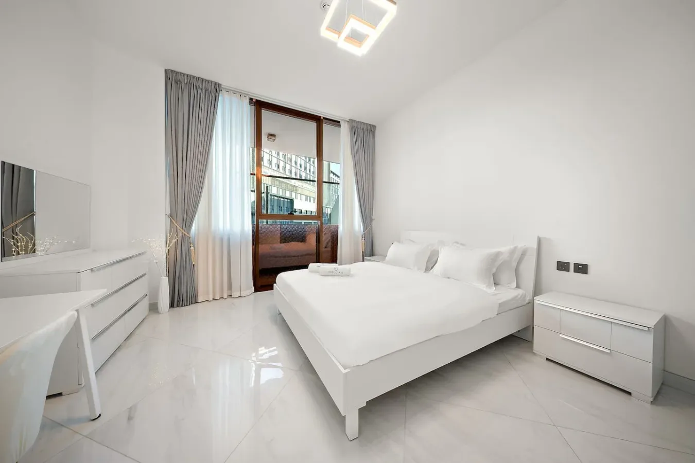 A bright bedroom with a large bed and glass doors opening to a balcony.