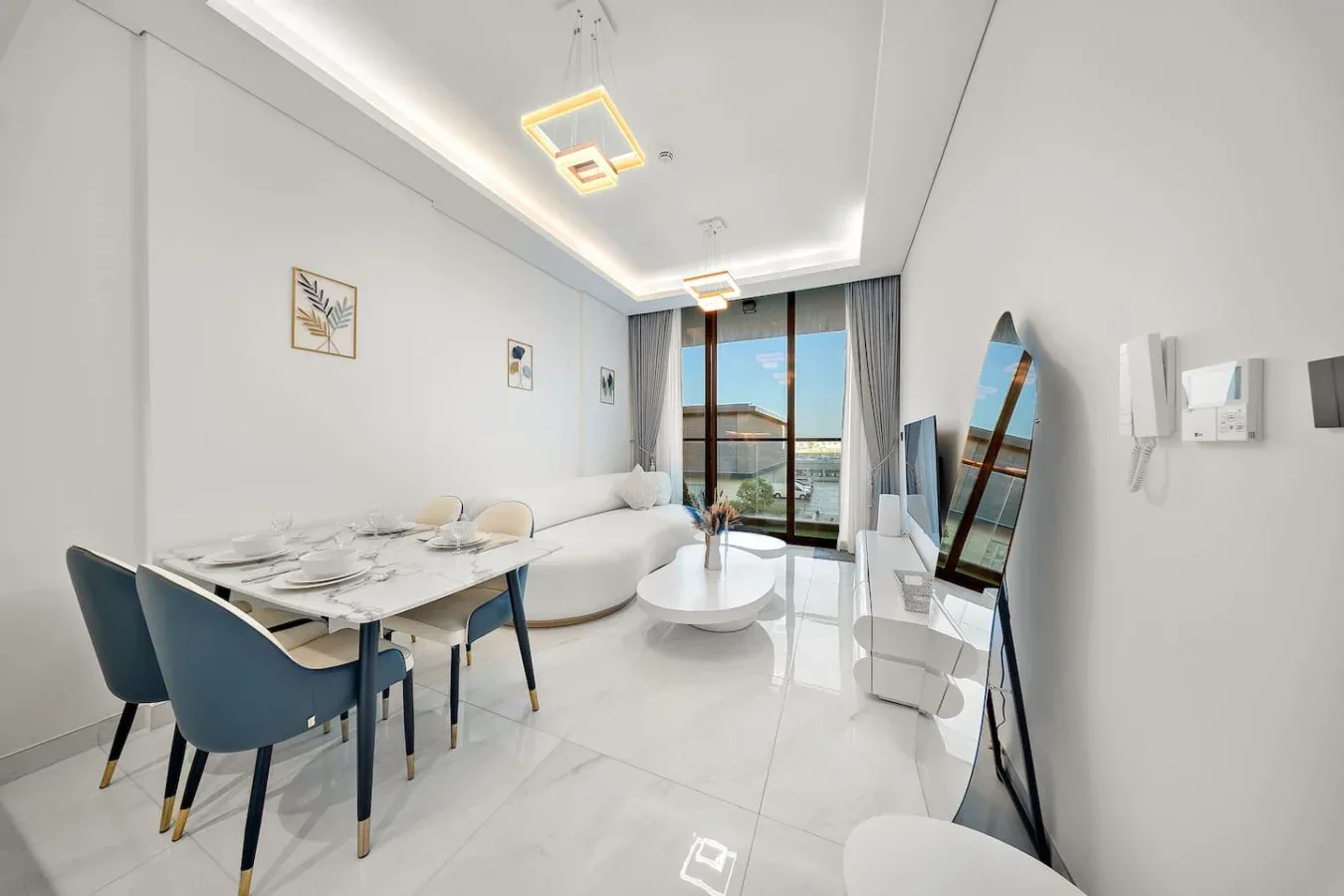A bright living and dining area with a table, seating, and large windows.