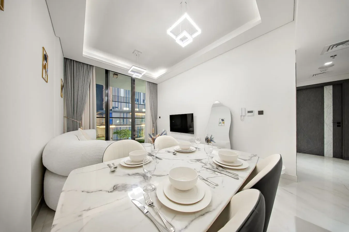 A bright dining area with a set table and a television in the background.