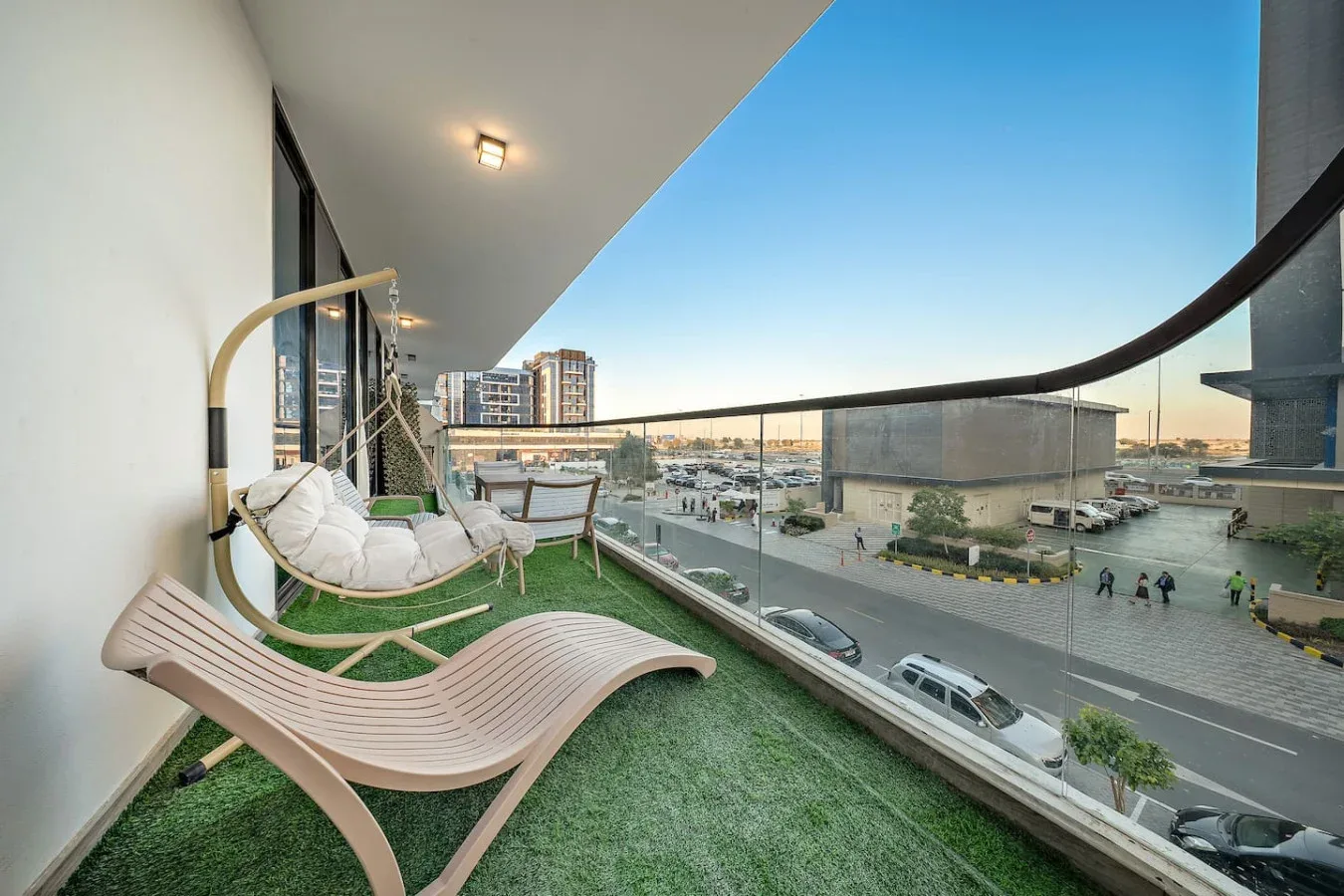 A balcony seating area with lounge chairs overlooks a city street.