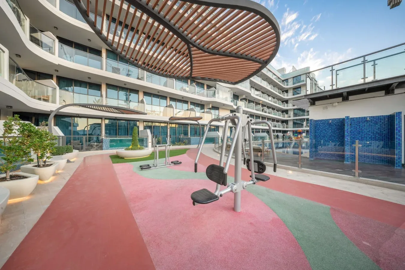 An outdoor fitness area with exercise equipment beside a modern building.