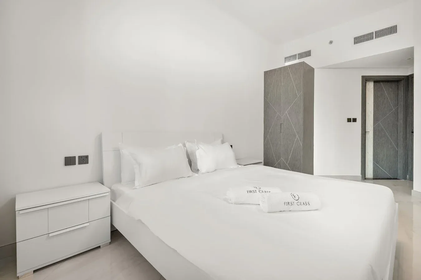 A bright bedroom with a large bed and white linens.
