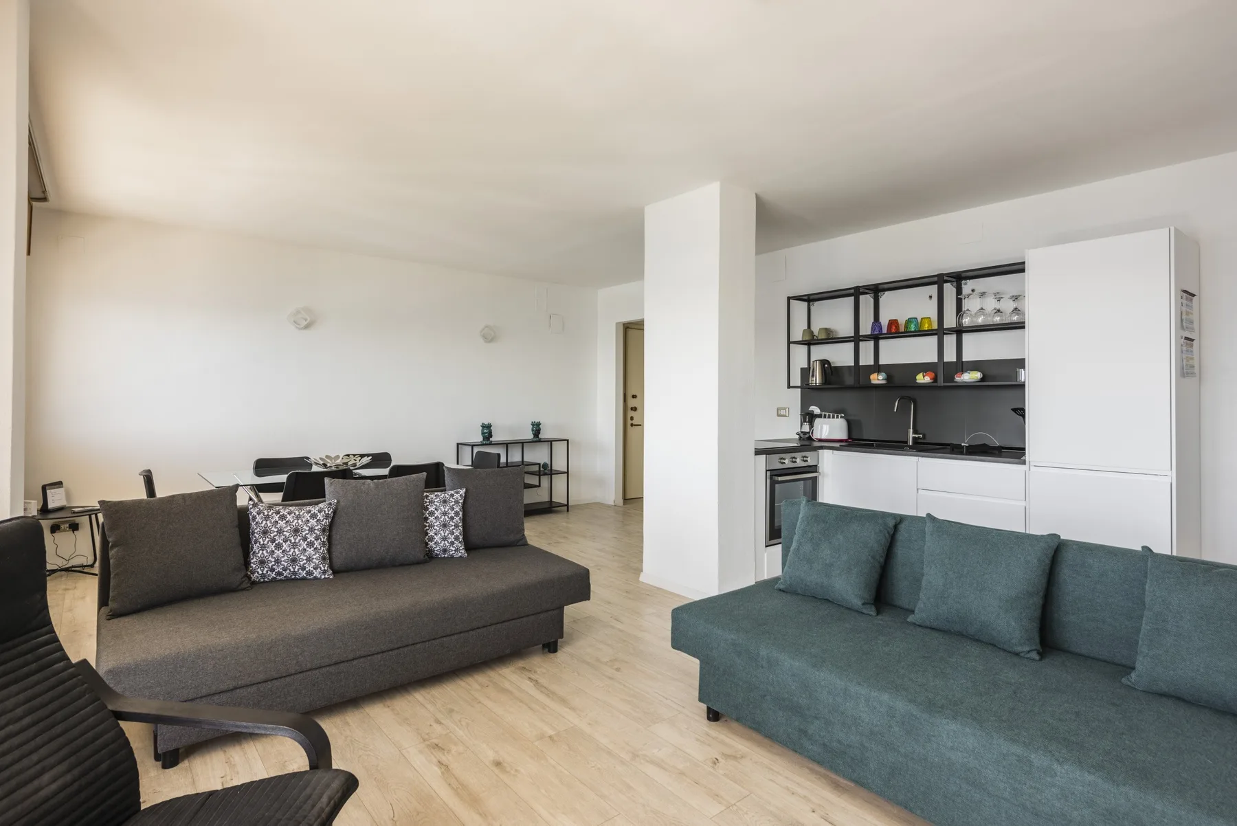Una sala de estar de planta abierta con sofás y una cocina al fondo.