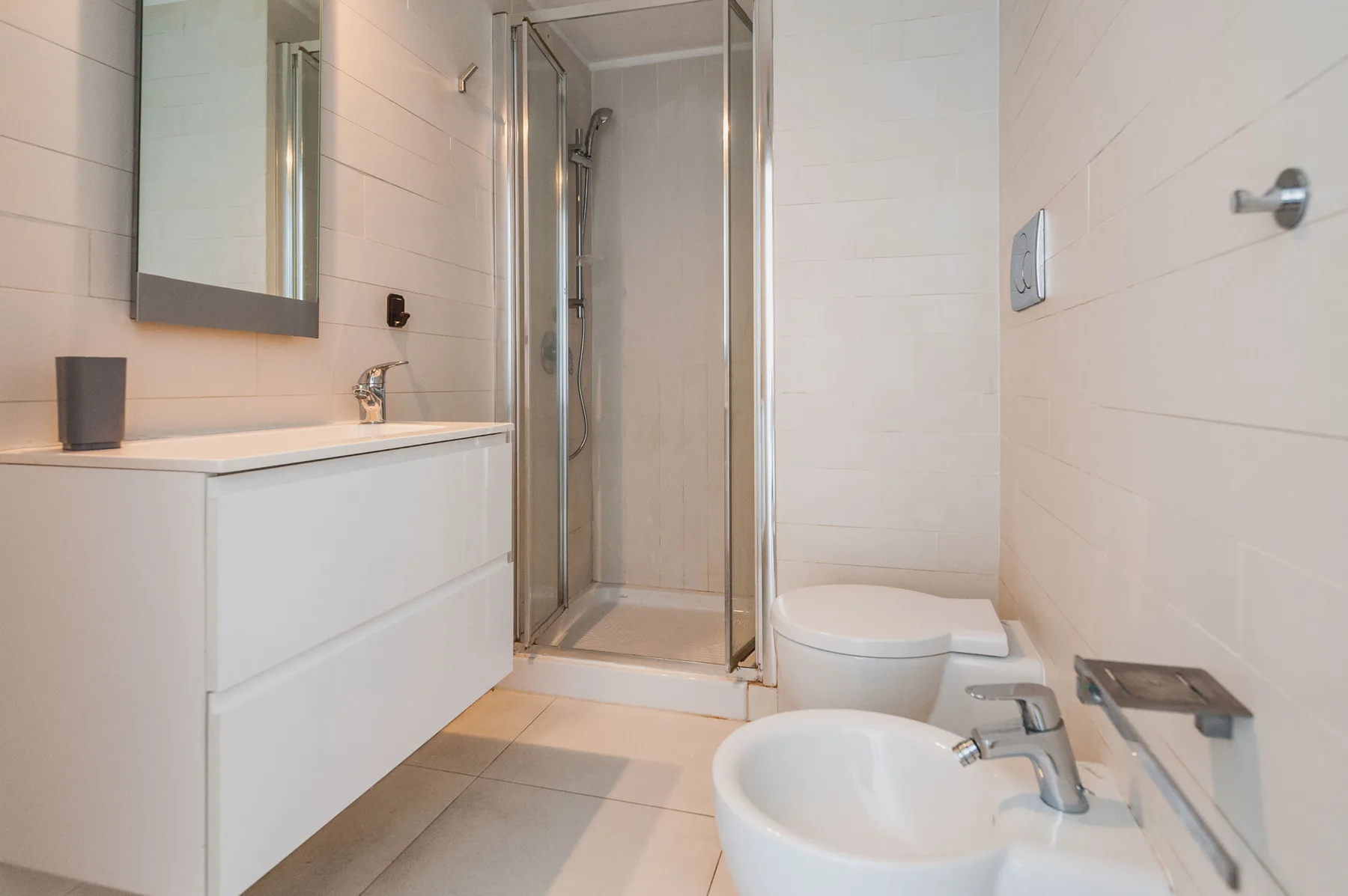 Un baño con azulejos, ducha, lavabo e inodoro.