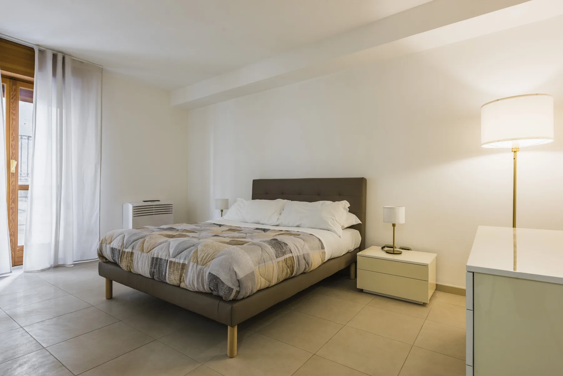 Un dormitorio con una cama bien hecha y muebles junto a la cama.