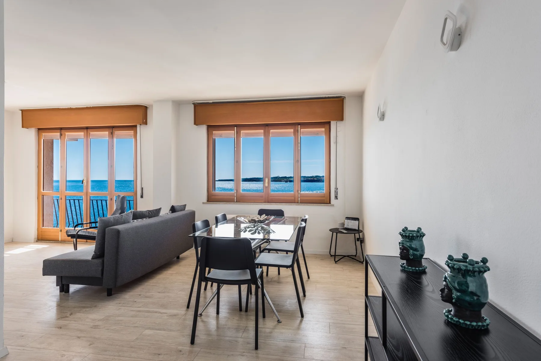 Una luminosa sala de estar y comedor tiene asientos y grandes ventanas con vista al mar.