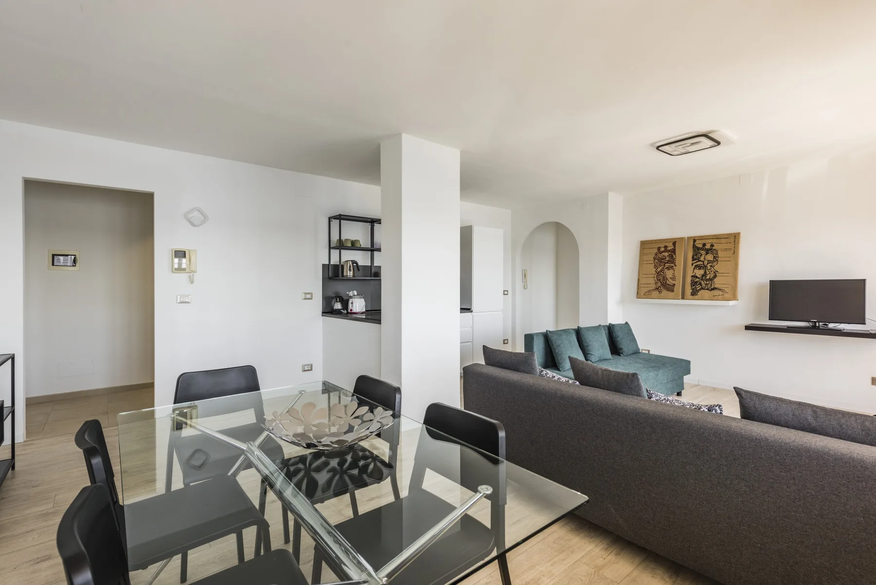 Una sala luminosa con una mesa de comedor de vidrio y asientos distribuidos por el espacio.