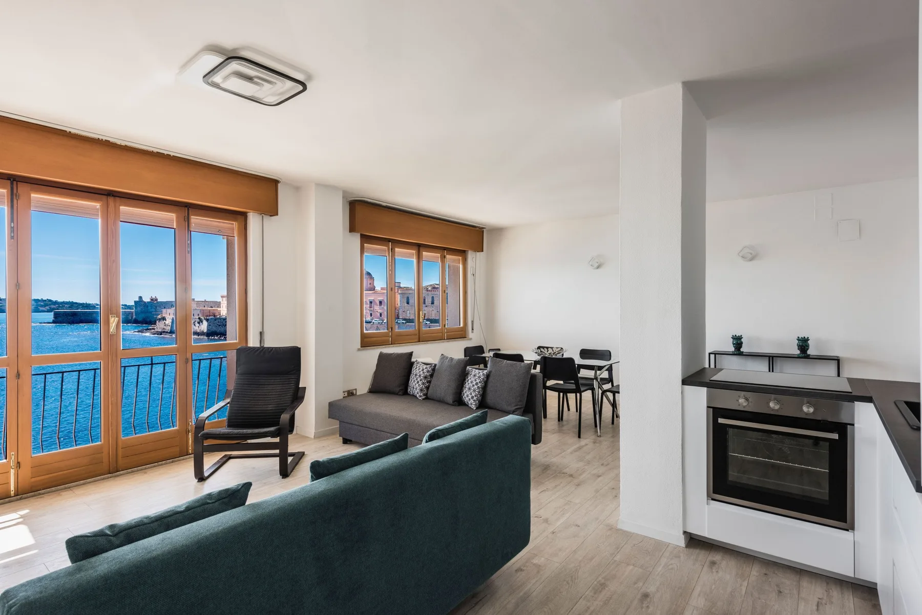 Una sala luminosa con zona de estar, comedor y grandes ventanas con vistas al agua.