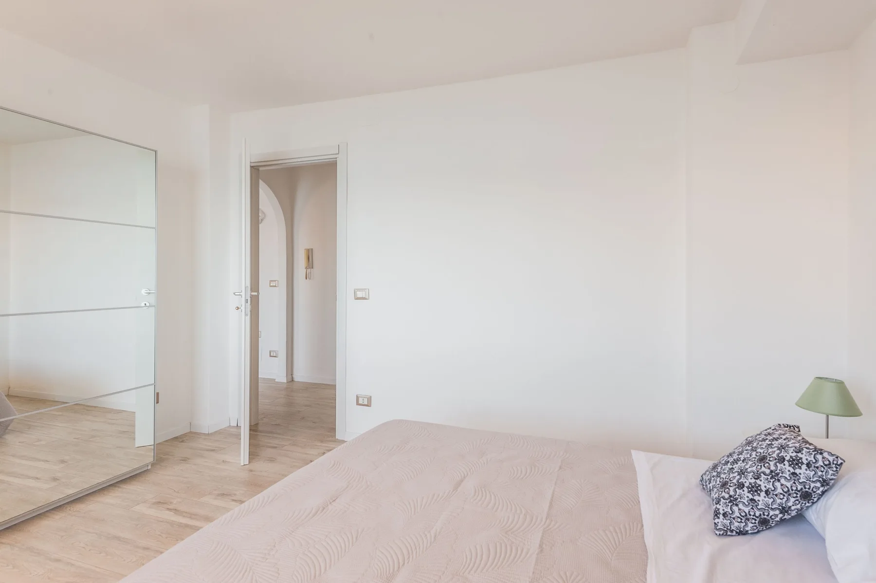 Un dormitorio luminoso con una cama y un armario con espejo.