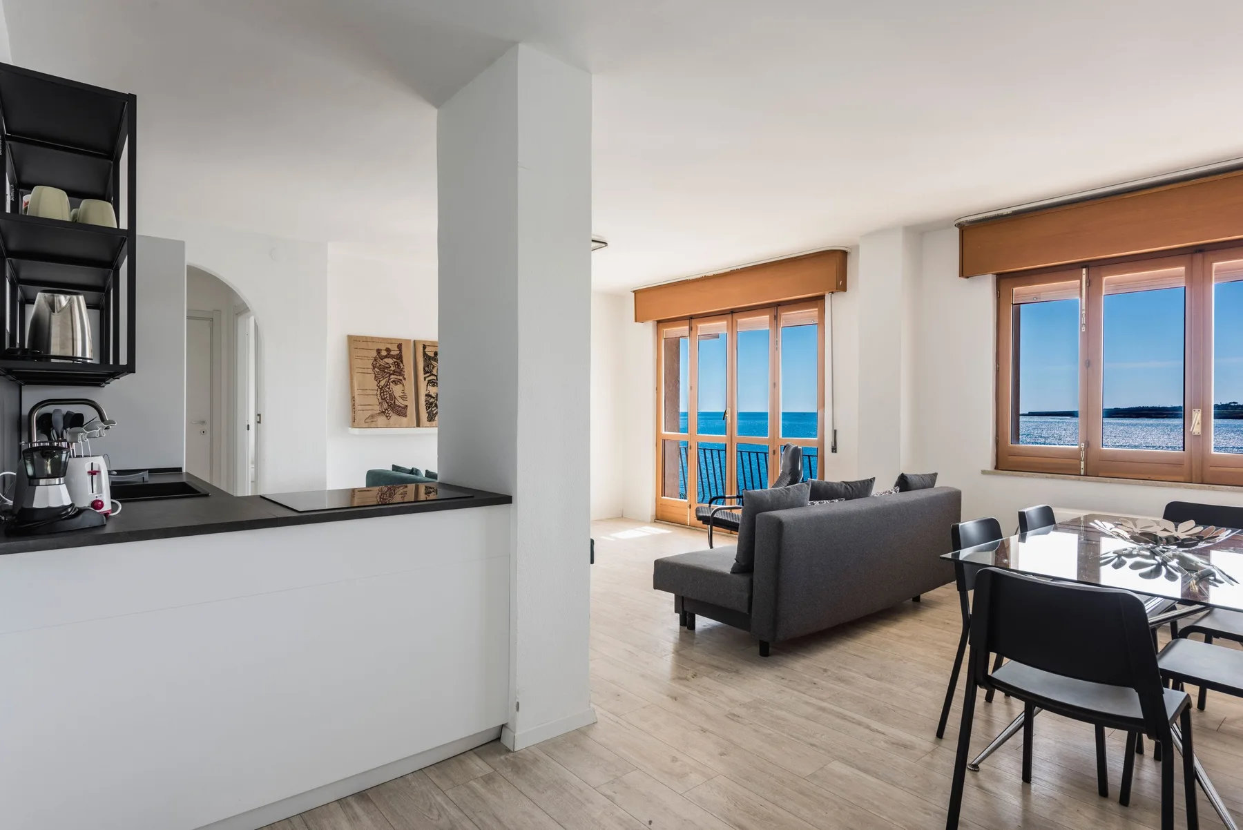 Una sala de estar y comedor de concepto abierto, con asientos y grandes ventanas frente al mar.