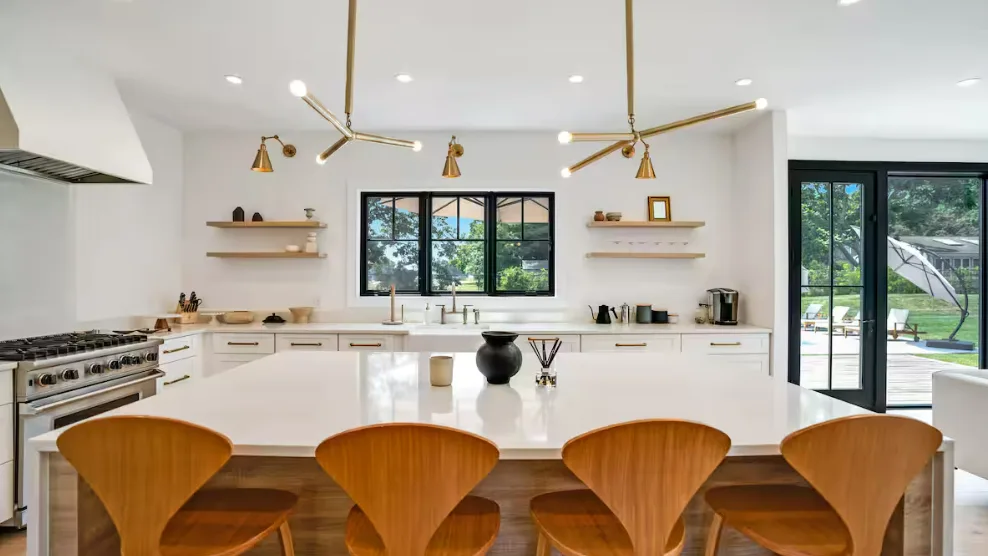 Una cocina luminosa con una isla grande y asientos de madera.
