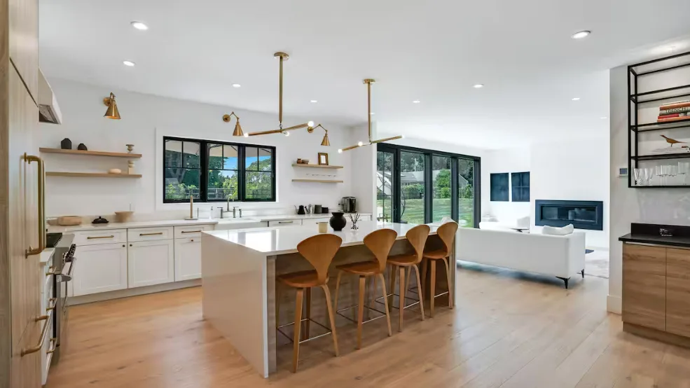 Una luminosa cocina abierta al salón, con una isla y asientos para comer.