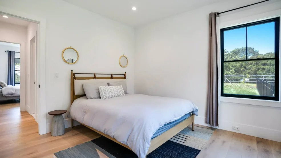 Un dormitorio luminoso con una cama bien hecha y una ventana grande.