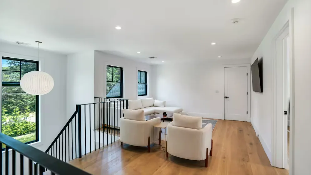 Una sala luminosa con asientos junto a una barandilla negra y ventanas grandes.