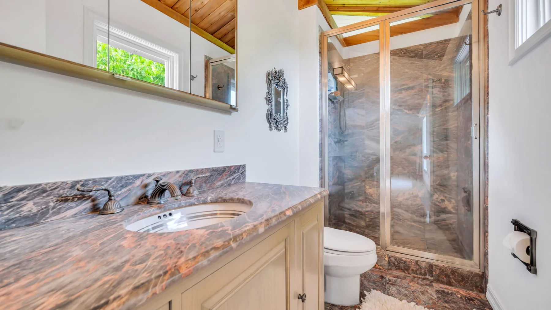 Un tocador de baño con lavabo está junto a una ducha de vidrio.
