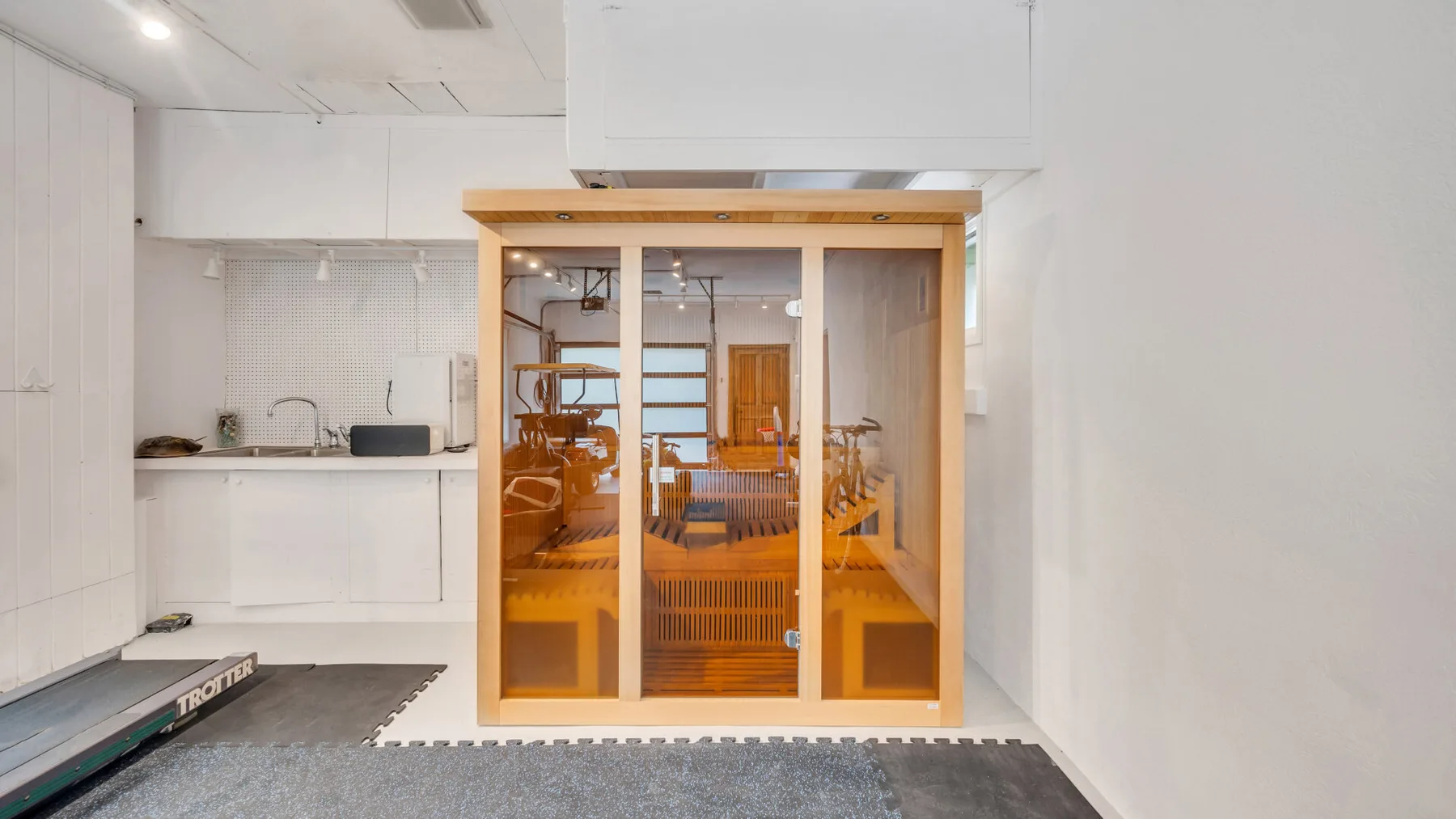 Una cocina luminosa da a un comedor tras puertas de vidrio con marco de madera.