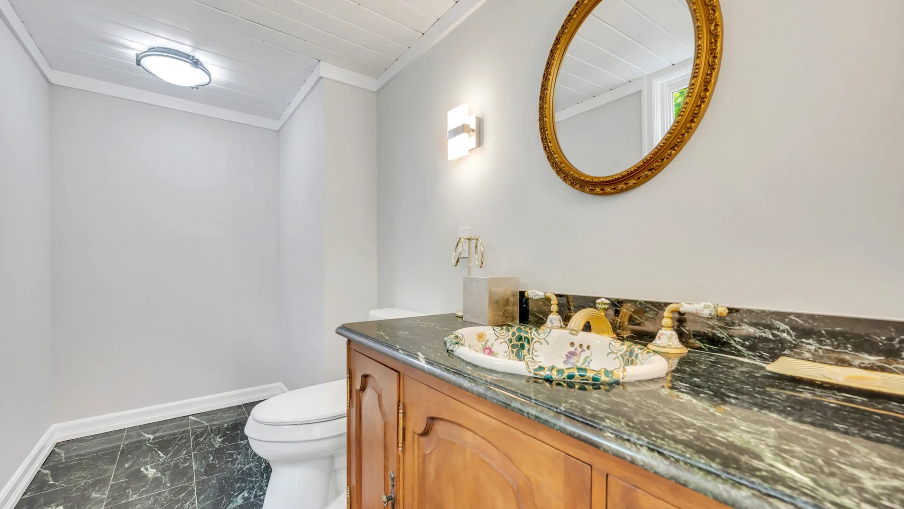 Un baño con un mueble de madera, un lavabo sobre la encimera y un espejo ovalado.