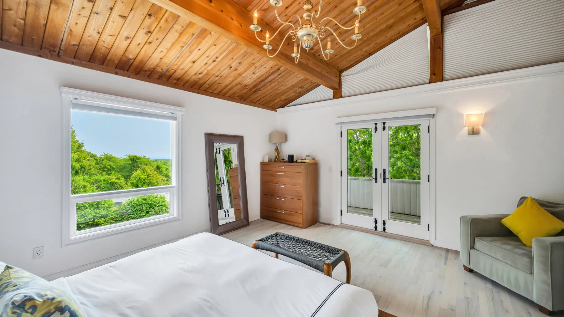 Un dormitorio luminoso con una cama, puertas corredizas de vidrio y techo revestido de madera.