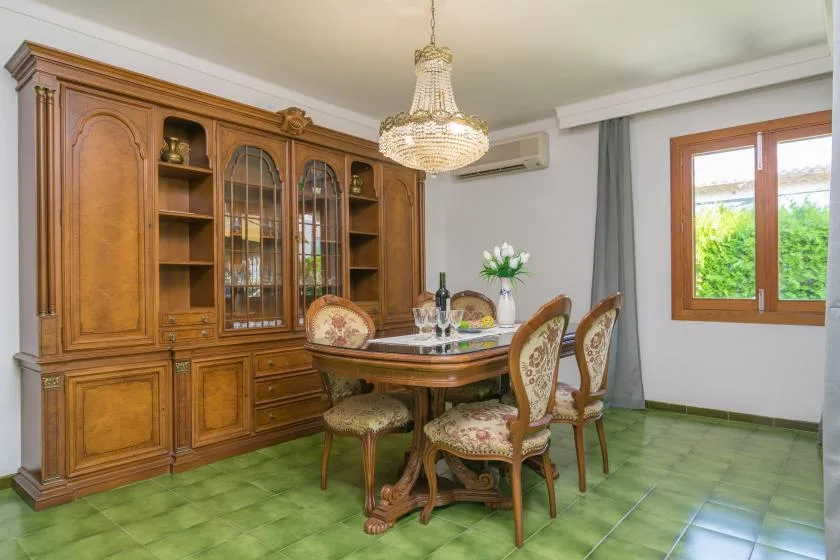 Comedor con una mesa de madera y sillas junto a un gran mueble vitrina.