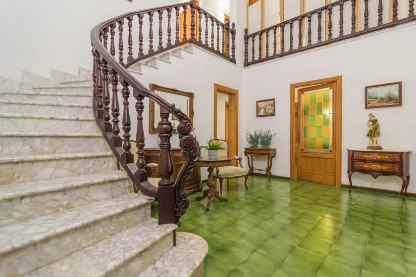 Un recibidor embaldosado con una escalera curva y barandilla de madera.