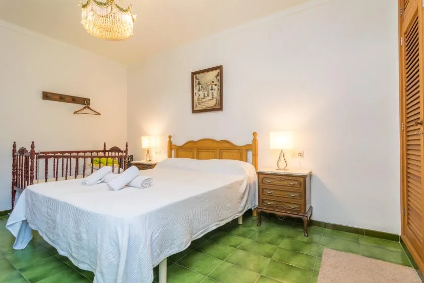 Un dormitorio con una cama grande, mesitas de noche y suelo de baldosas verdes.