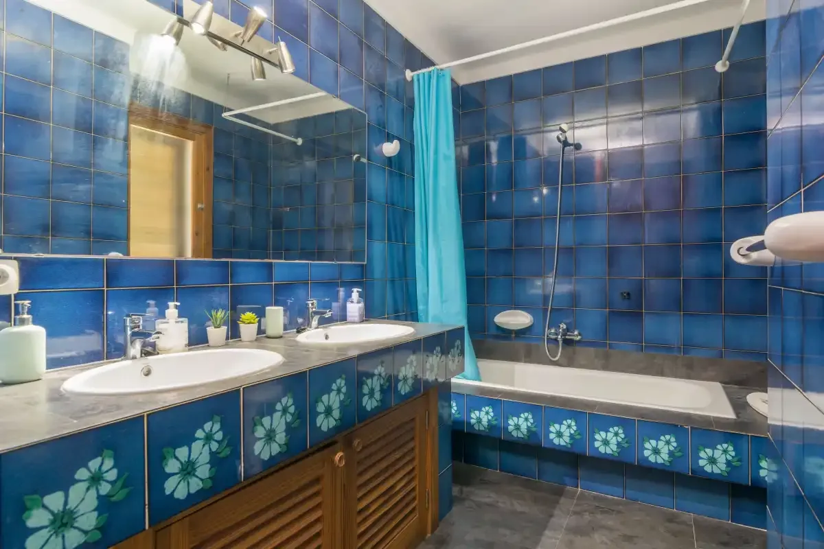 Un baño alicatado con bañera, ducha y lavabo doble.