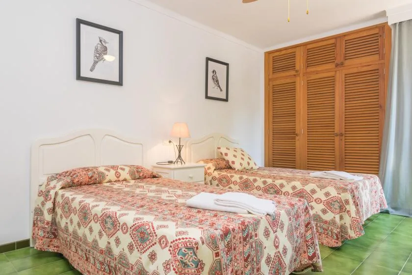 Un dormitorio con dos camas, ropa de cama estampada y puertas de armario de lamas de madera.