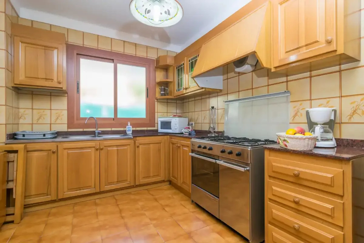 Una cocina con armarios de madera, una encimera y una estufa.