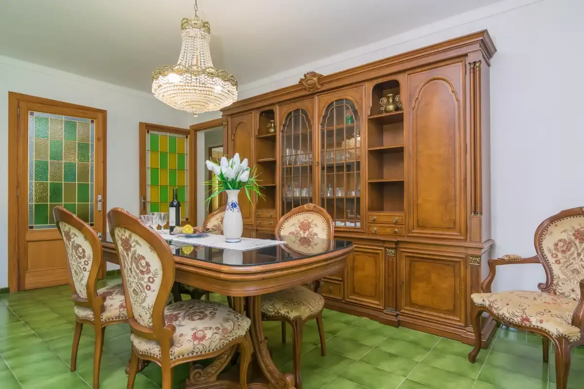 Comedor con una mesa de madera y sillas bajo una lámpara de araña.