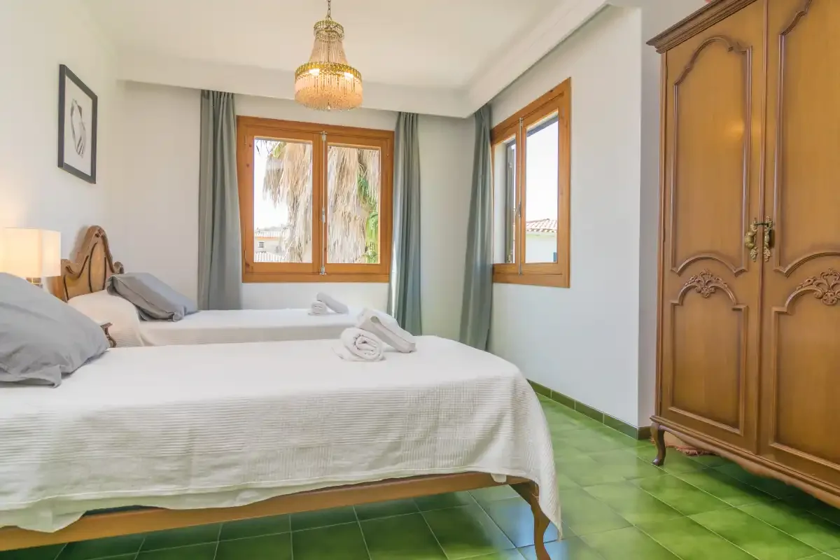 Un dormitorio con ropa de cama blanca, ventanas de madera y un armario de madera tallada.