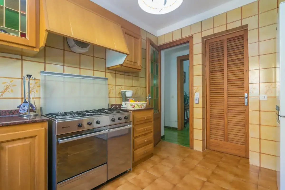 Una cocina alicatada con estufa, armarios de madera y una puerta.