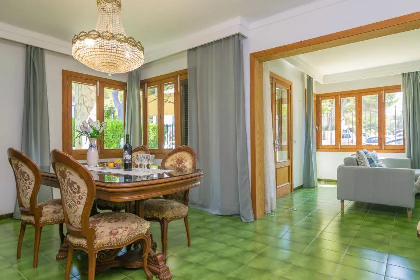 Comedor con mesa y asientos junto a una luminosa sala de estar.