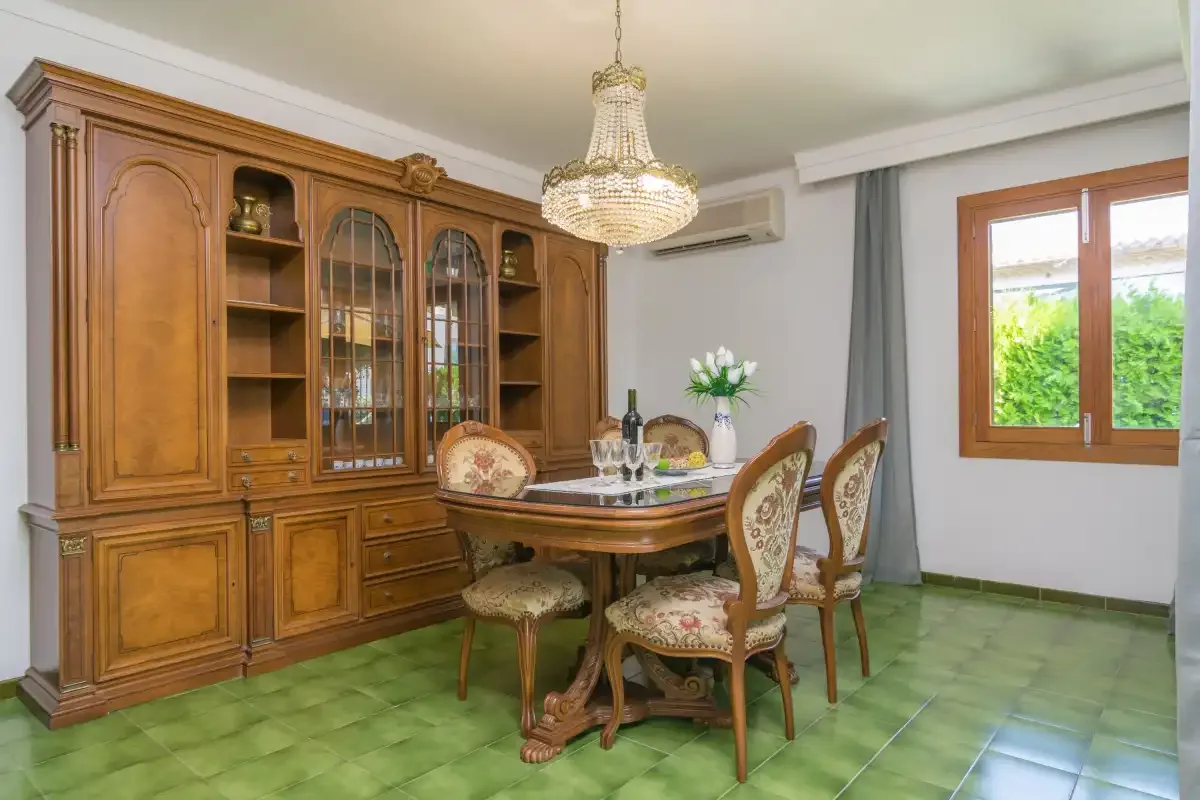 Un comedor con una mesa de madera y sillas junto a un gran mueble vitrina.