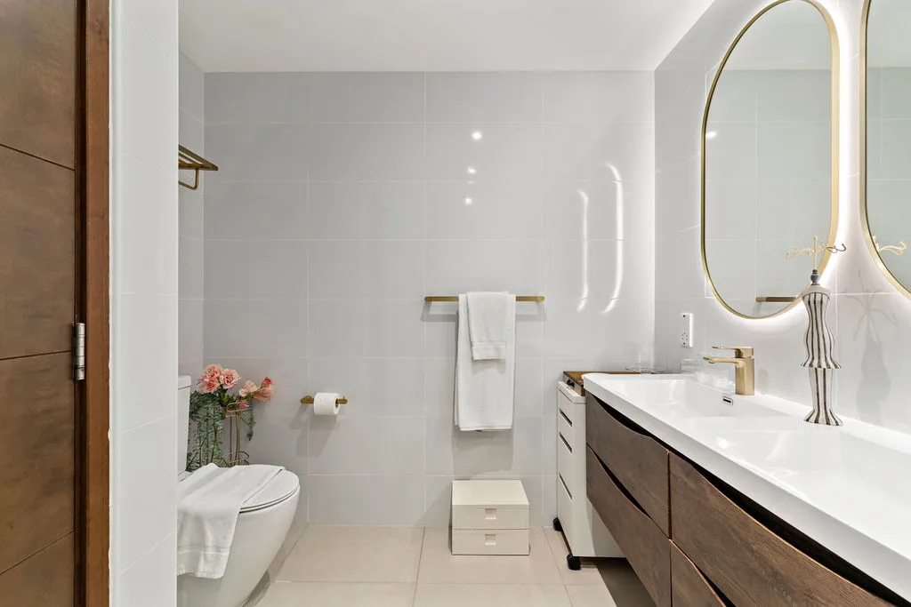 A bright bathroom with a vanity, sink, and wall mirror.