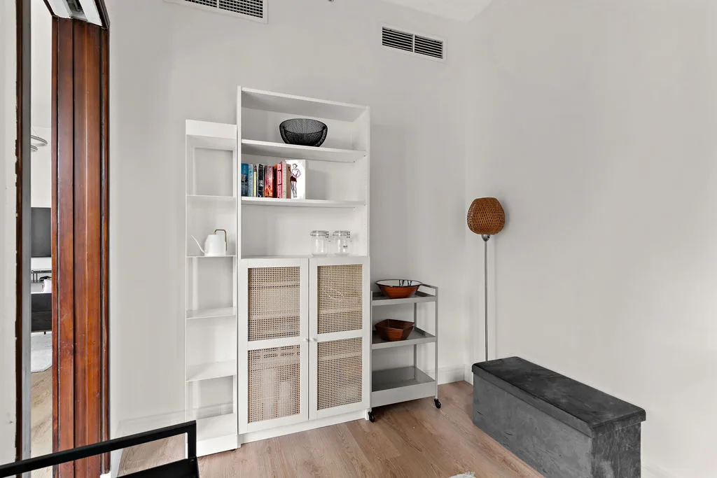 A bright room with white shelving, a low bench, and a wooden floor.