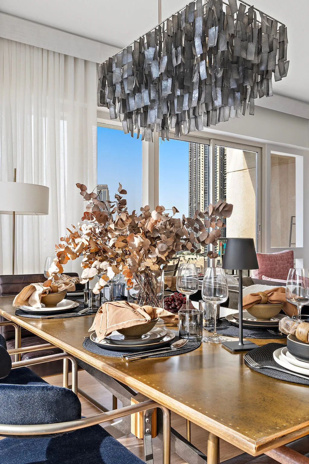 A dining area with a set table beneath a large hanging light.