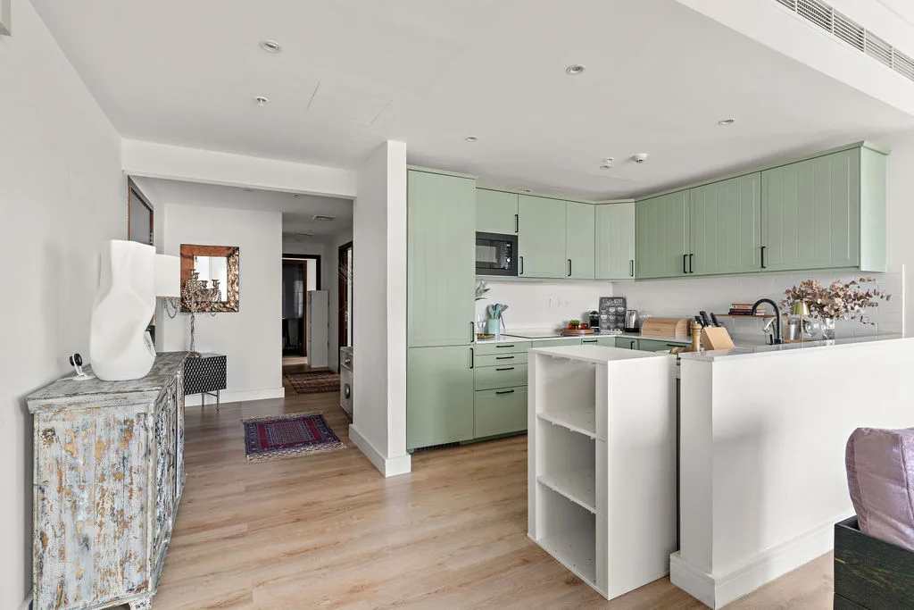 A bright kitchen with pale green cabinets and a white island.