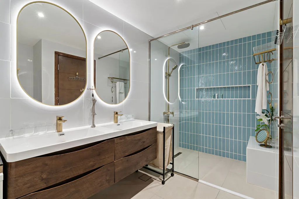 A modern bathroom with a double vanity and a glass-enclosed shower.