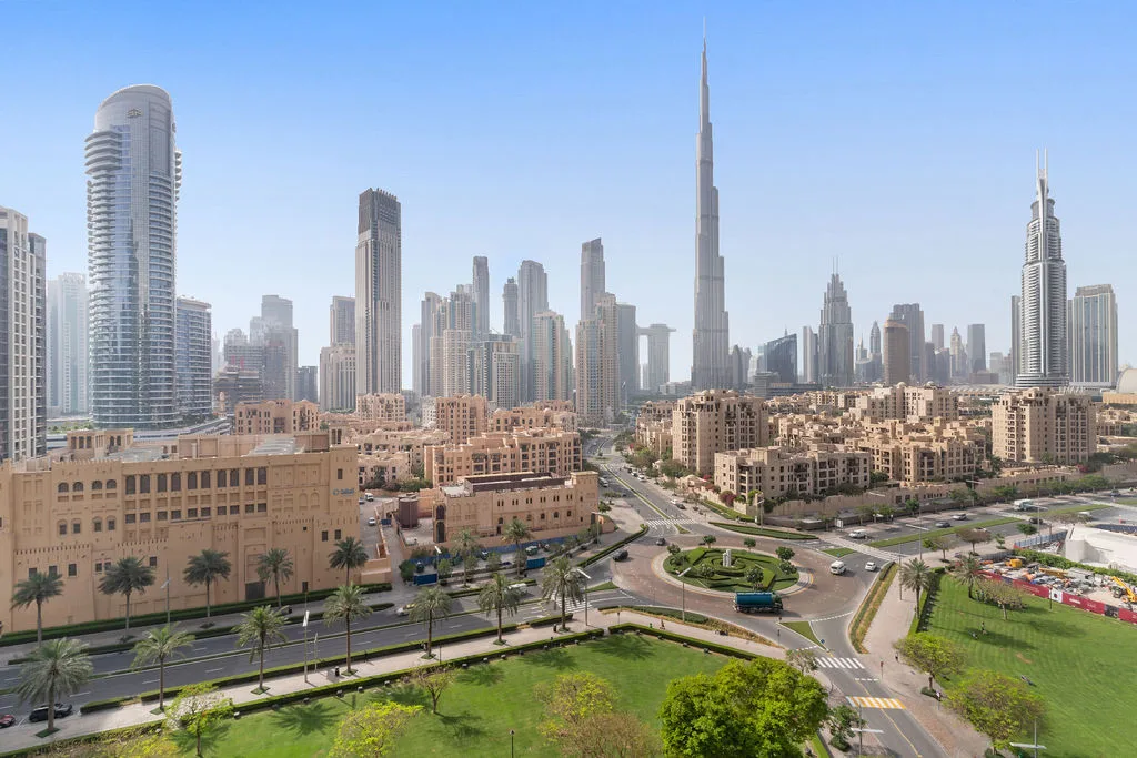 A city skyline with the Burj Khalifa rising above roads and low-rise buildings.