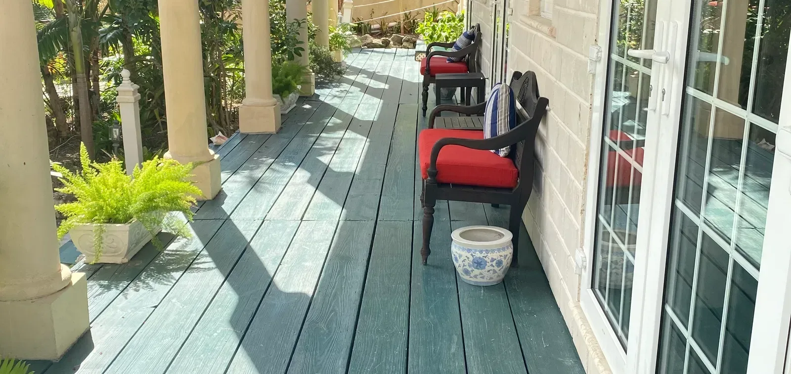 Pasillo exterior con suelo verde y sillas rojas