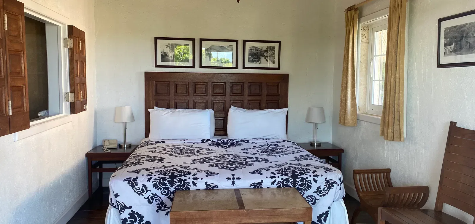 Dormitorio con una cama grande, mesa, silla y obras de arte enmarcadas