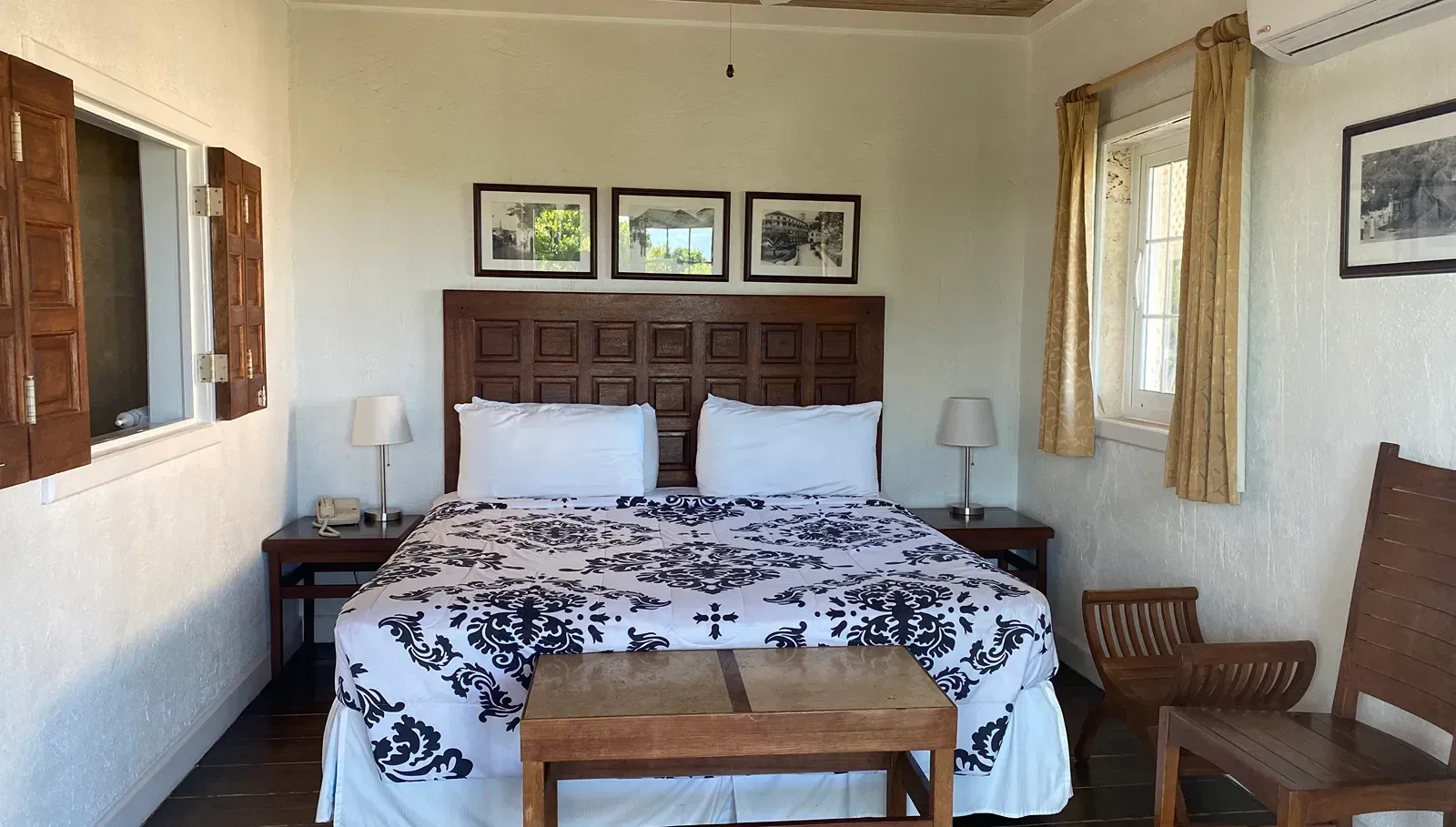 Dormitorio con una cama grande, mesa, silla y obras de arte enmarcadas