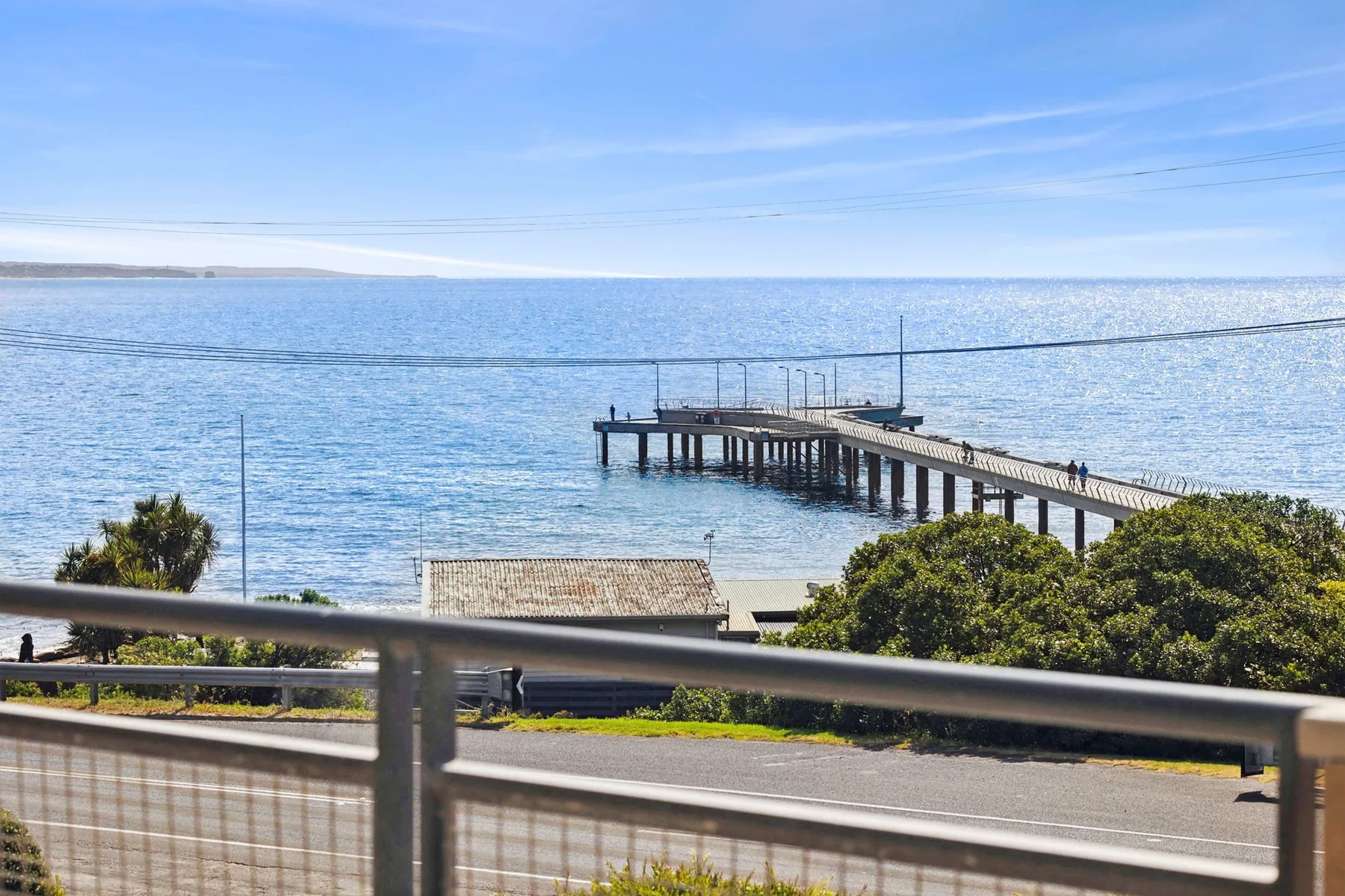 A seaside view shows a long pier extending over the water.