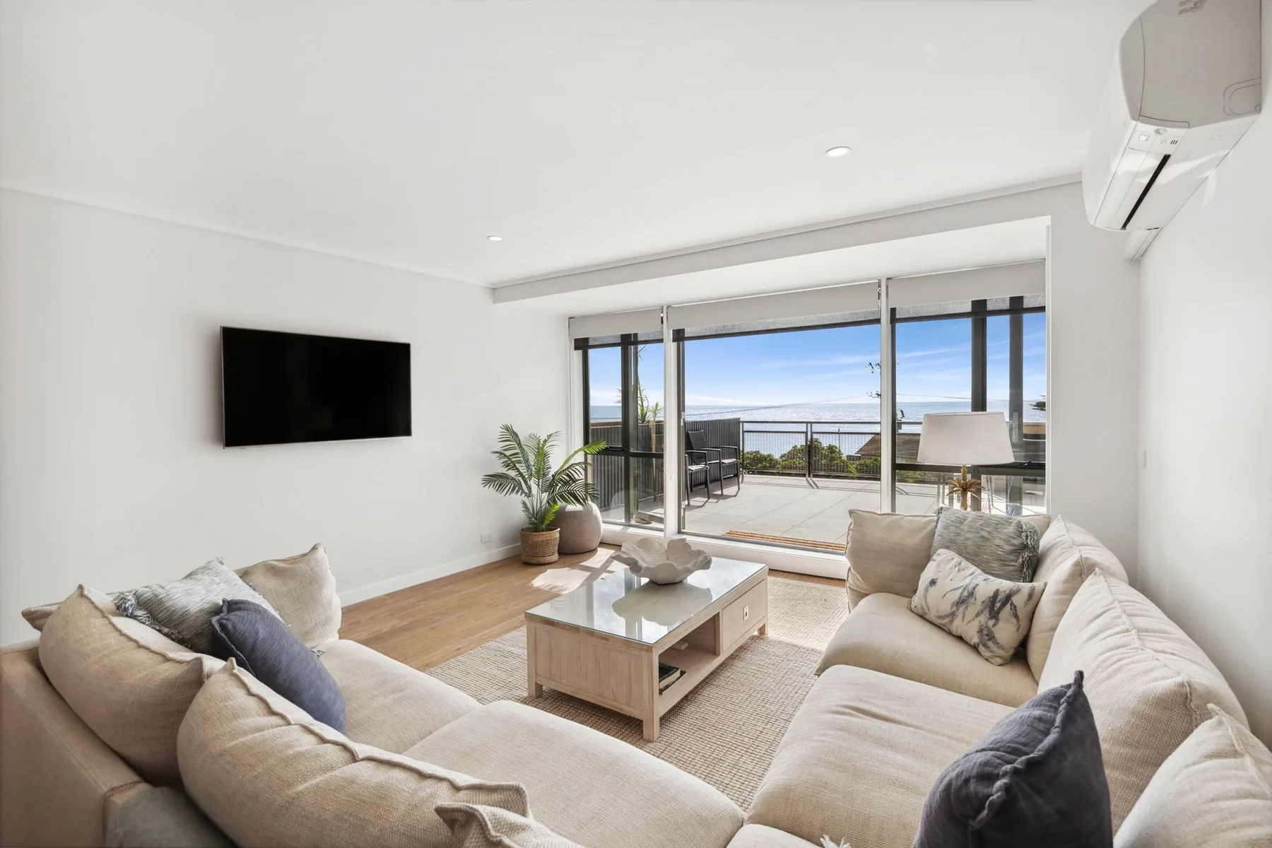 A bright living room opens onto a balcony through wide sliding glass doors.