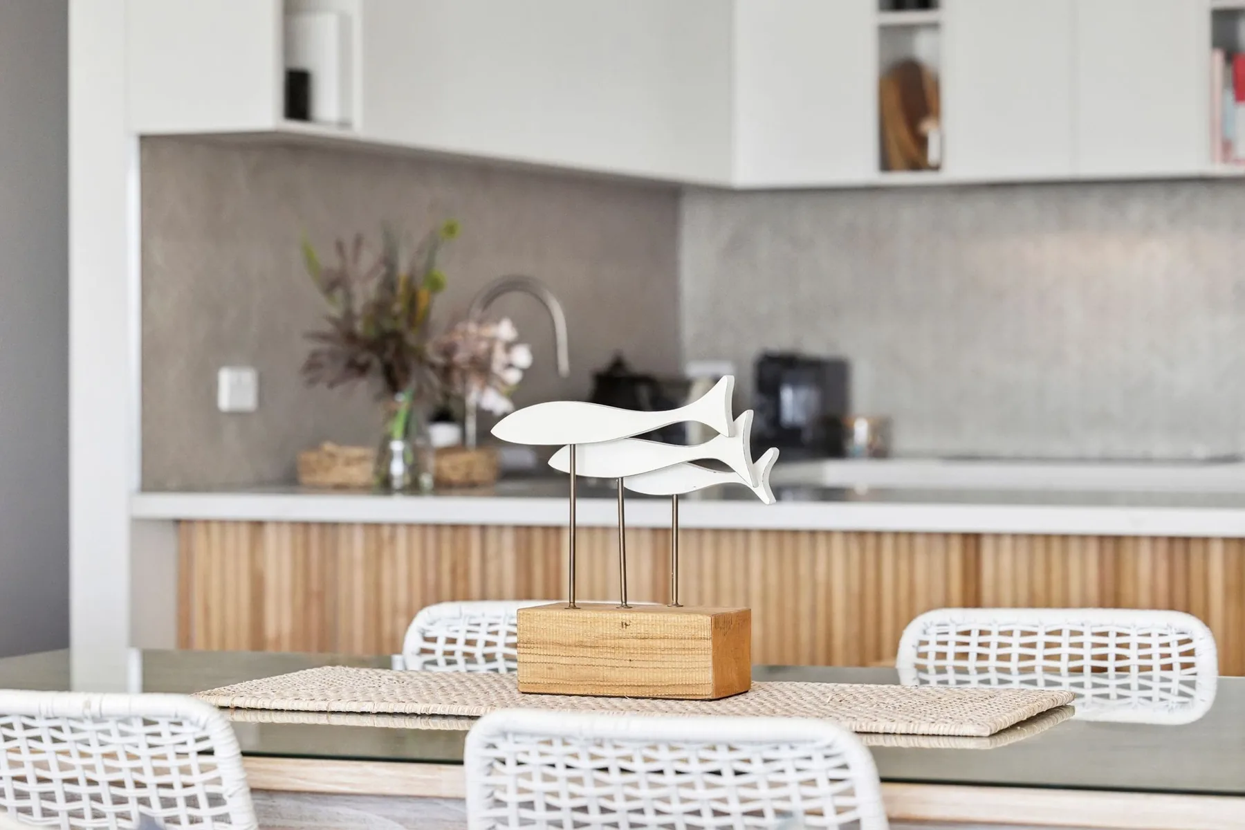 A dining area with woven seating and a sculptural centerpiece on the table.