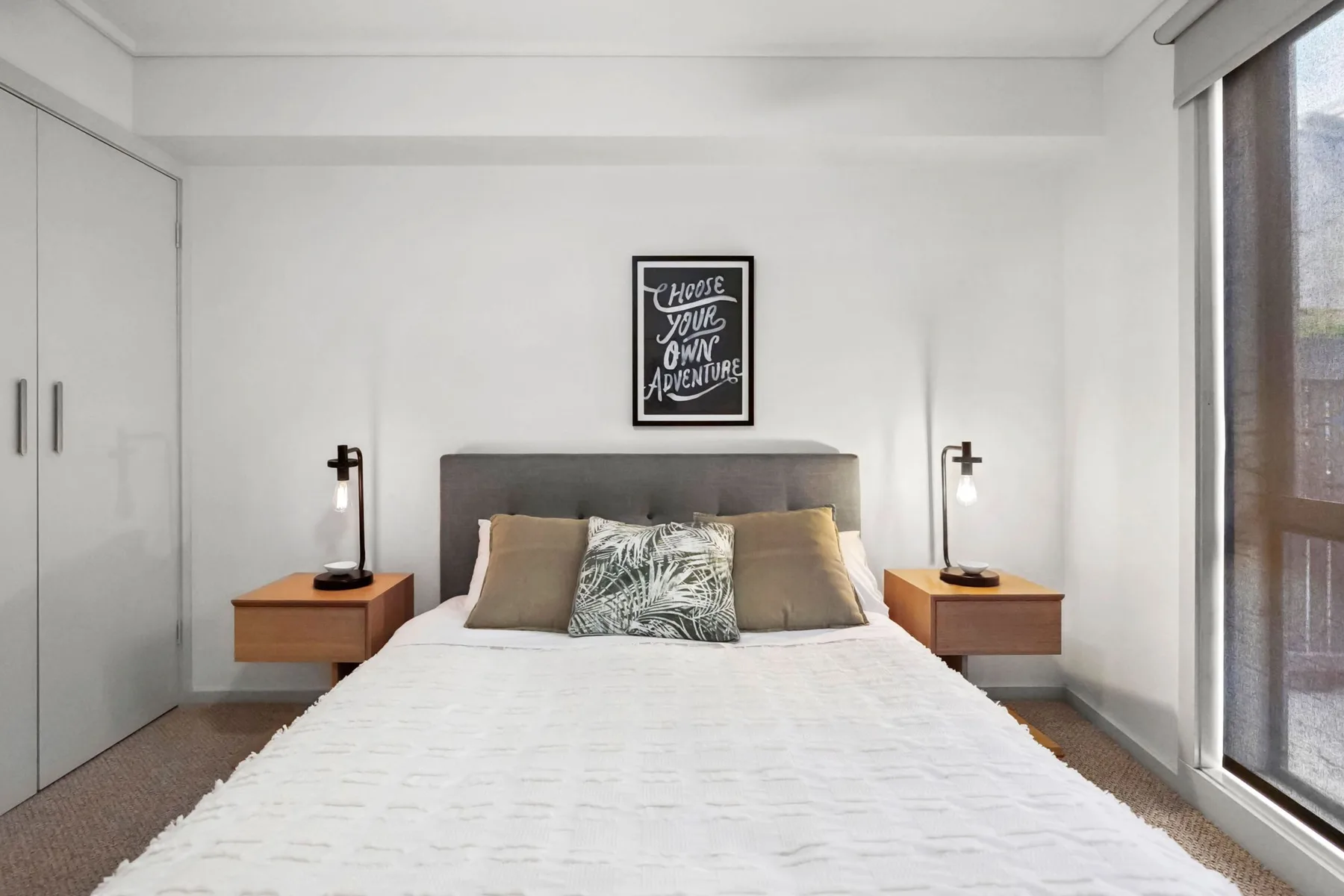 A bright bedroom with a neatly made bed and matching bedside tables.