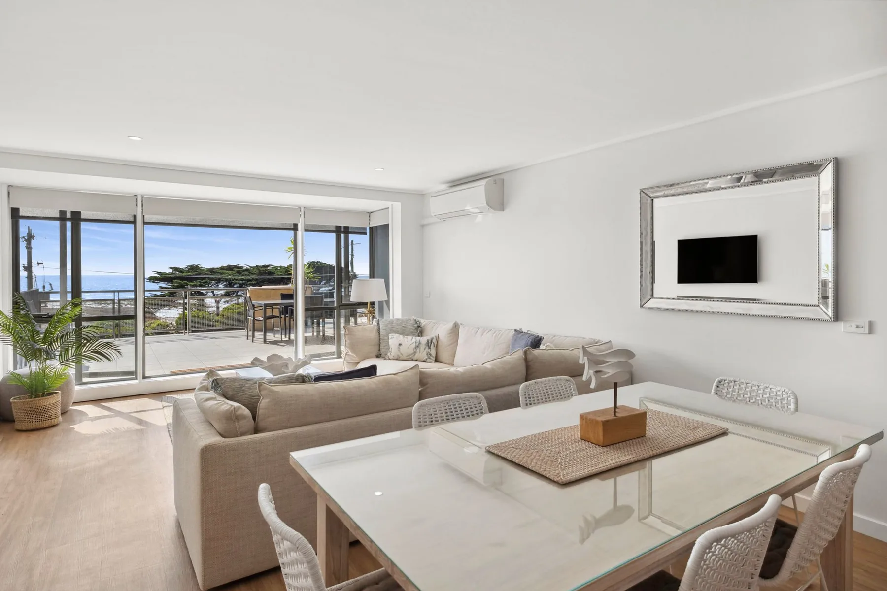 A bright living and dining area opens onto a balcony through wide glass doors.
